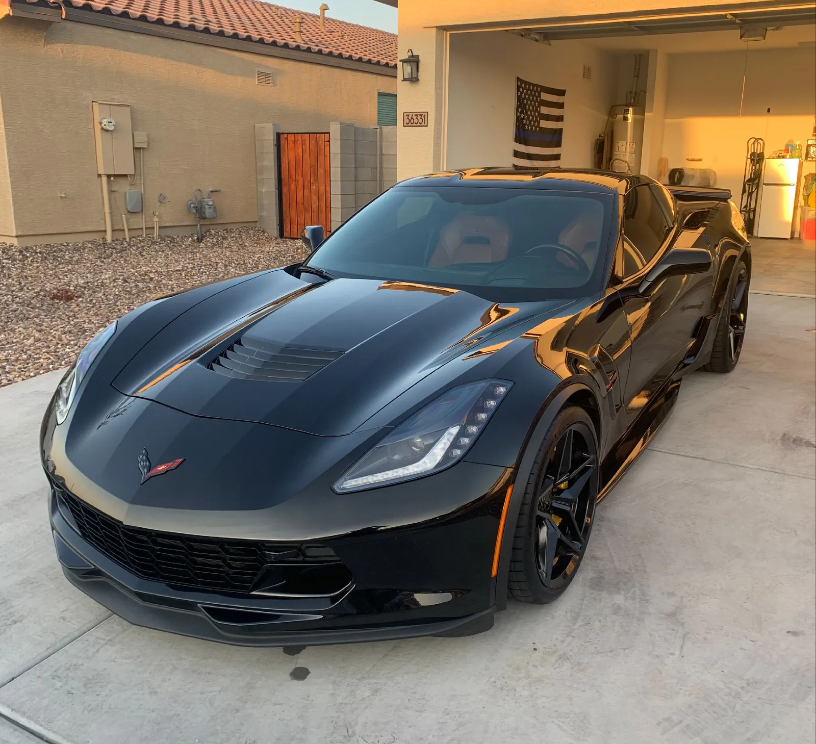 A black Corvette detailed in a driveway at golden hour