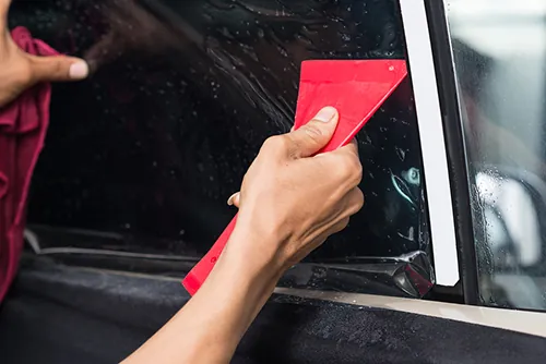A squeegee pressing window film onto glass